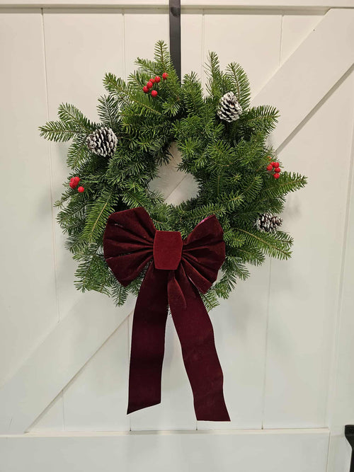 Christmas wreath with a red bow on a white door