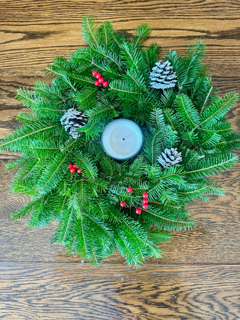 Christmas center piece with a candle on a wooden surface